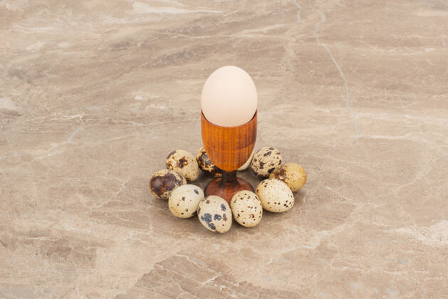生鸡蛋几只鹌鹑蛋围着白蛋放在大理石桌上生鸡蛋鹌鹑生鸡蛋