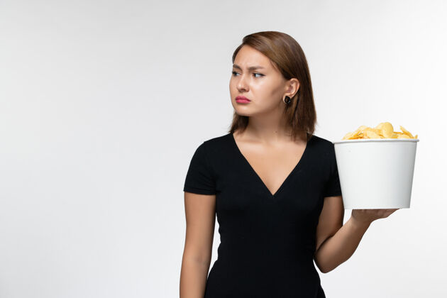 马铃薯正面图身穿黑色衬衫的年轻女性在白色的表面上拿着薯片孤独秘书电影