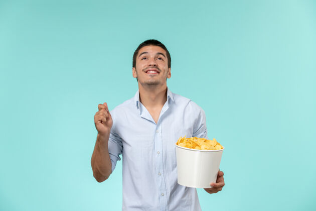剧院正面图：年轻男性拿着蓝桌子上的薯片篮子电影实验室外套土豆