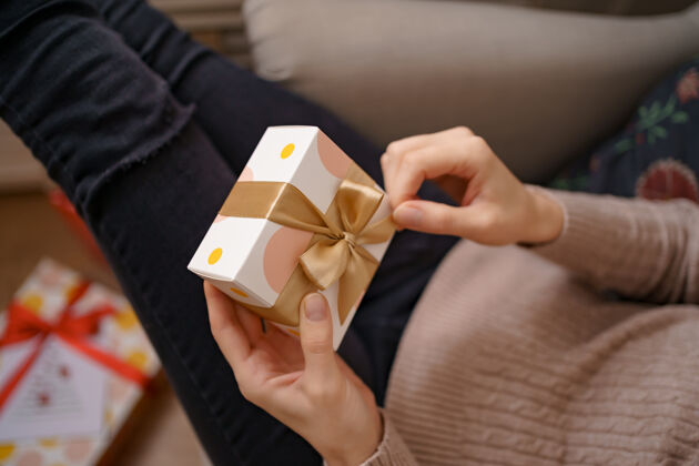 手工制作女人手里拿着包好的白色盒子和金色的蝴蝶结 专注于盒子庆祝准备礼物