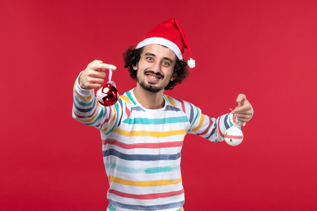 举行正面图年轻人手持圣诞树玩具在红墙新年红色假期肖像漂亮成人