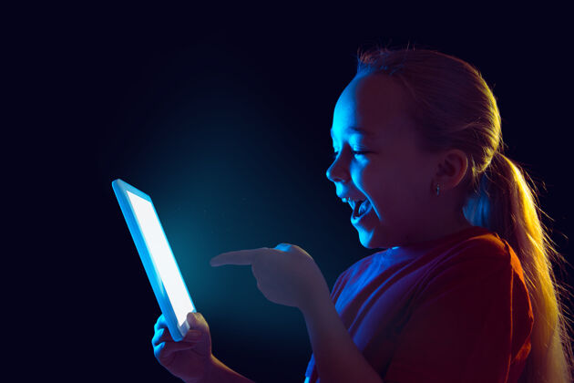 专业霓虹灯下拿着平板电脑的小女孩表达人情感