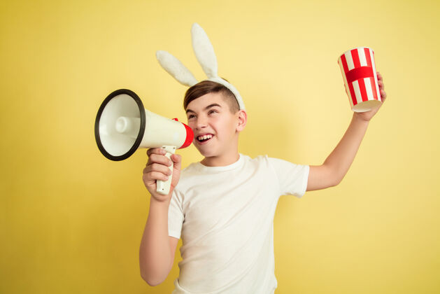 惊喜在黄色的墙上像复活节兔子一样的男孩肖像节日兔子