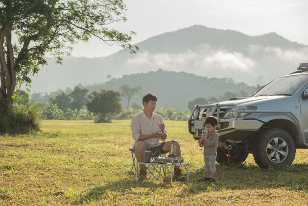 活动一家人在露营车旁野餐日落时分父子俩在山上玩耍包国家放松