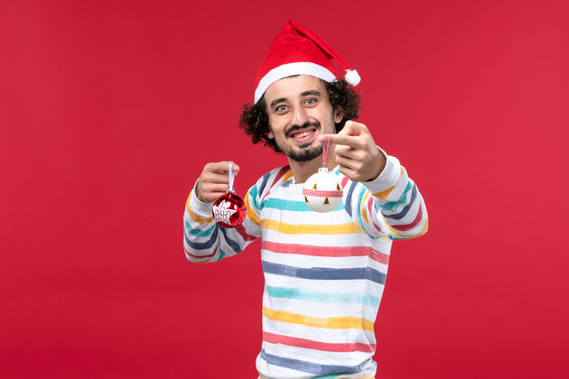 球员正面图：年轻人手持圣诞树玩具在红墙新年红色假期人成人肖像