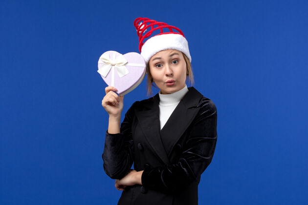 举行正面图年轻女士手持心形礼物在蓝色墙上新年礼物圣诞节成人经理