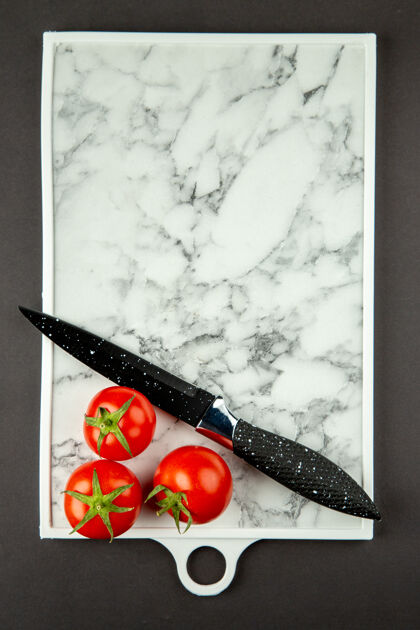 营养黑色表面上有红色西红柿的白色砧板俯视图刀大理石鹅毛笔
