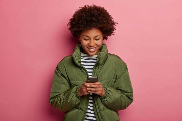 满意快乐的美国黑人少年手持手机 专注于屏幕 穿着水手套头衫和冬衣 查看收入信息 在闲暇时间在线观看视频女性室内欢呼