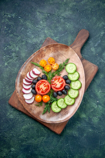 胡椒新鲜切碎的蔬菜在一个棕色盘子里的垂直视图在混合颜色背景的木制砧板上午餐盘子饮食