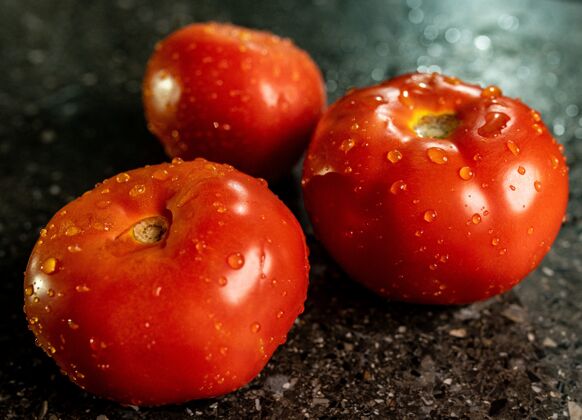 生的特写新鲜成熟的西红柿水滴在一个黑色花岗岩厨房台面新鲜膳食地中海