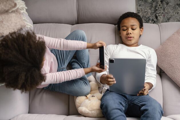 兄弟兄弟姐妹在家使用平板电脑和手机科技男孩设备