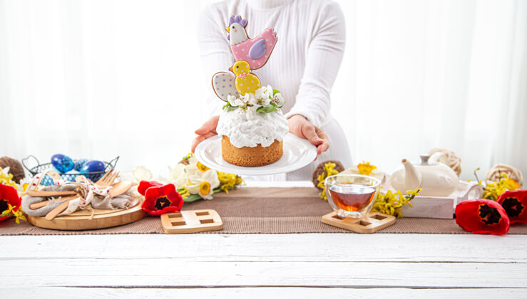 春天女人手里拿着一个节日的复活节蛋糕 上面装饰着鲜花和鲜艳的细节准备复活节假期的概念设置女人鸡蛋