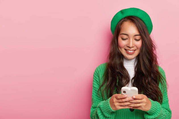 套头衫时尚漂亮的亚洲女孩拿着手机 穿着绿色衣服 用现代手机上网 发短信女性电子服装