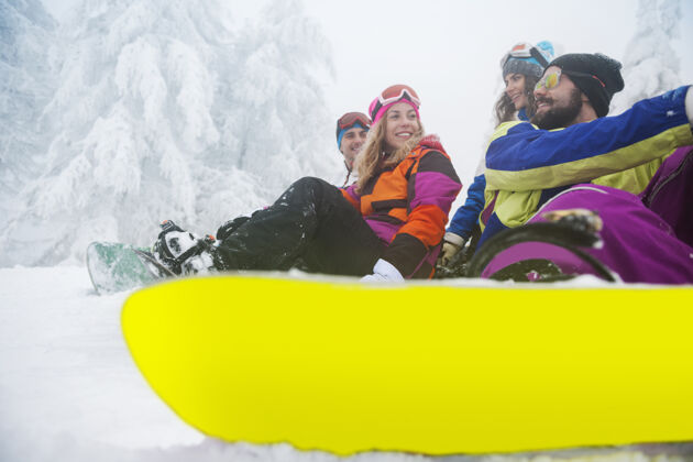 雪两对情侣在玩滑雪山峰团队牙牙学语的微笑