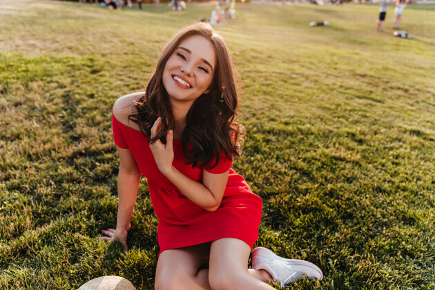 放松优雅的红衣少女坐在草地上快乐的黑发女孩在草地上摆姿势减肥快乐肖像