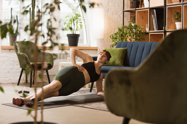 健康坐沙发锻炼年轻女子在家锻炼女性蹲运动