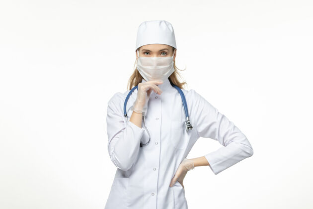 面罩因冠状病毒而戴口罩和手套的女医生正穿着医疗服 思考白色书桌病病毒冠状病毒-大流行性疾病正面到期冠状病毒