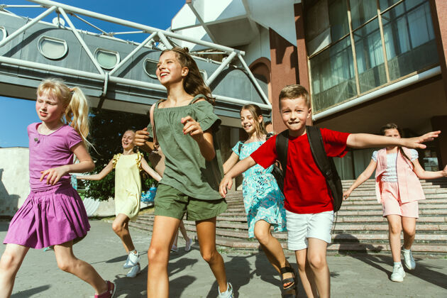 街道在阳光明媚的夏日 快乐的孩子们在城市的街道上玩耍 一群快乐的孩子或青少年在一起玩耍休闲积极跑步