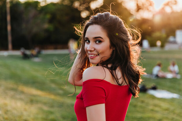 优雅夏日里 优雅的黑发女孩在公园里摆姿势一位身着红色连衣裙的年轻女士愉快地欣赏着大自然的景色微笑花园服饰