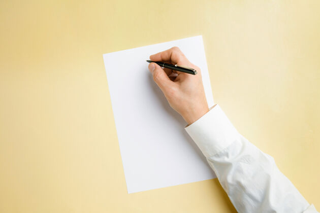 营销男性手持笔 在黄色墙壁上的空白纸上书写文字或设计空白模板用于联系 广告或商业 金融 办公 采购复制空间手臂显示工人