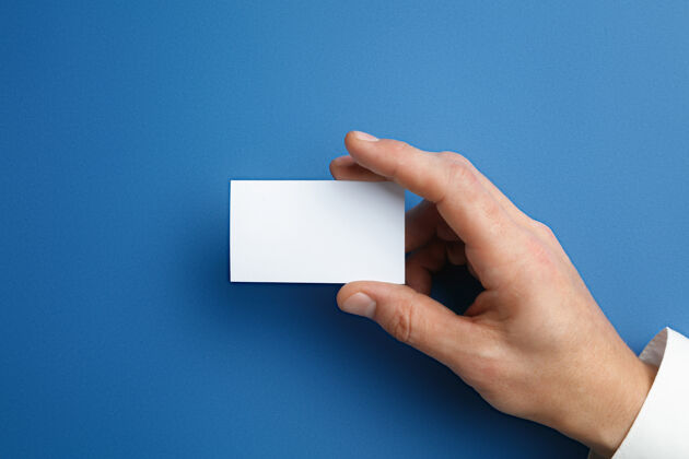 明亮男性手拿一张空白名片放在蓝色的墙上 用于文字或设计空白信用卡模板用于联系或在商业 金融 办公室使用复制空间空白办公室握住