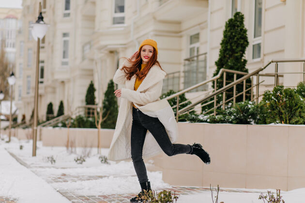 欢呼穿着白大褂的温文尔雅的女孩在冬日跳跃梦幻女人享受寒冷天气的户外照片年轻女子雪冬天