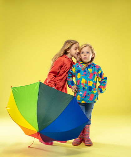 雨衣黄色工作室墙上 一个穿着雨衣 手持彩虹色雨伞的时尚女孩的完整肖像女学生休闲靴子
