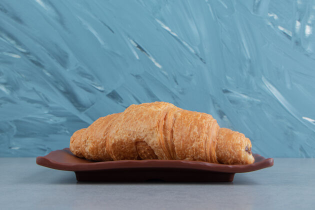 牙粉美味的羊角面包放在盘子里 大理石背景上高质量的照片美味牛角面包糖