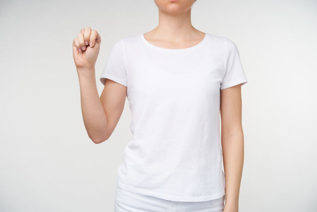 提高一个穿着休闲服的年轻女士站在白色背景上 手举着 用聋哑字母表显示字母n的水平镜头沟通女人符号