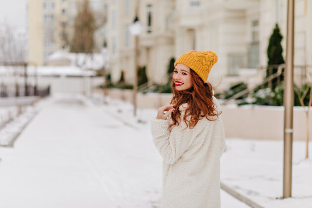 脸快乐的姜女在冬城漫步时回首往事优雅的欧洲女孩在下雪的早晨寒冷人散步积极