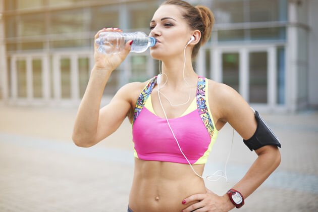 耳机年轻女子户外运动水在日常饮食中非常重要跑步运动休息