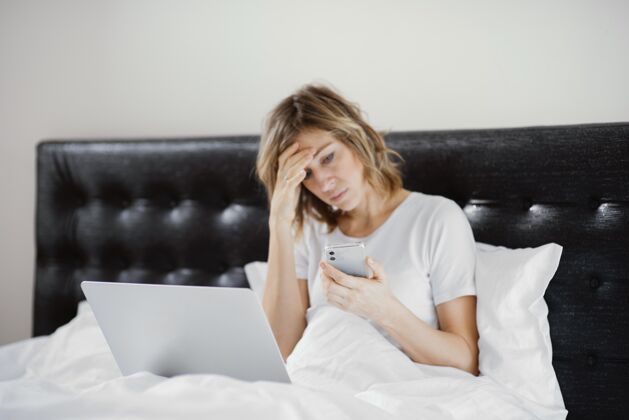 卧室女人在床上使用笔记本电脑和手机科技上瘾女人