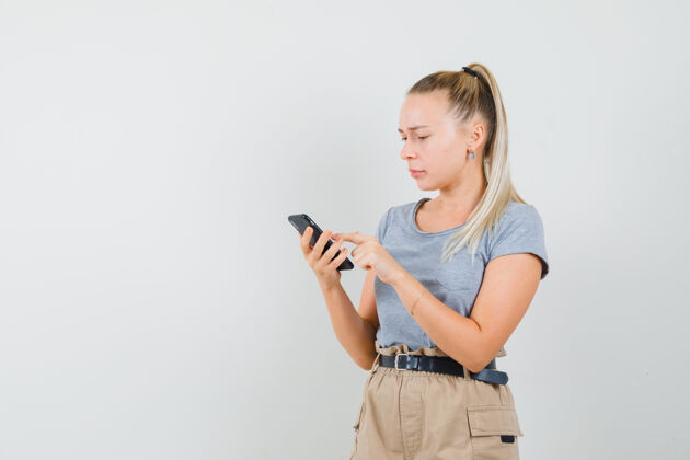 成人年轻女性穿着t恤 裤子用手机看热闹 前视图手机黑发肖像