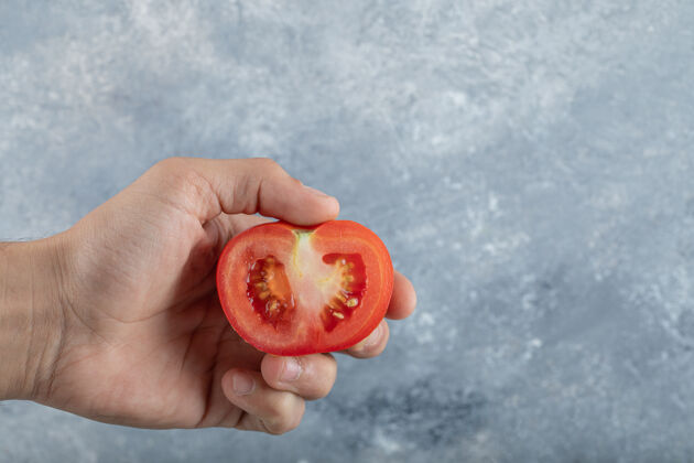 食物男人手里拿着一片红番茄高质量的照片卡路里对象单一