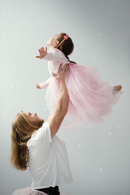 男性爸爸和女儿穿着短裙跳舞的侧视图男人世界各地垂直