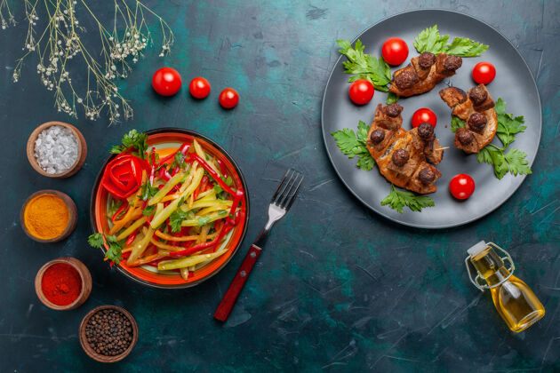 橄榄俯视图：深蓝色桌上的橄榄油沙拉和调味料炒肉片蔬菜食品肉类健康餐深蓝色盘子油