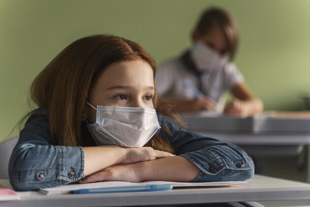 流行病戴着医用口罩的孩子在课堂上听老师讲课学校面罩冠状病毒