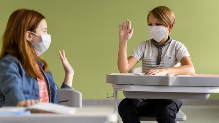 新常态戴着医用口罩的孩子们远远地互相击掌病毒学校学习