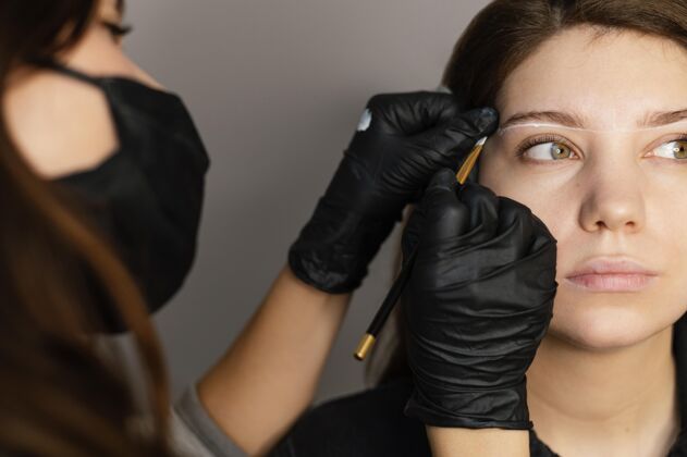 临床医生从女临床医生那里得到眉毛治疗的妇女的正视图美容面膜女人
