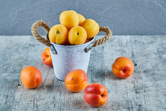 食谱美味的熟杏子放在铁桶里 油桃放在大理石表面甜多汁水果