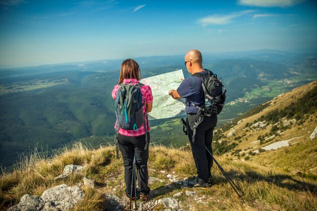 自然一对夫妇在看斯洛文尼亚纳诺高原上俯瞰维帕瓦山谷的地图活动徒步蓝色