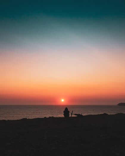 风景日落时一个人坐在岸边的剪影自然日落海岸线