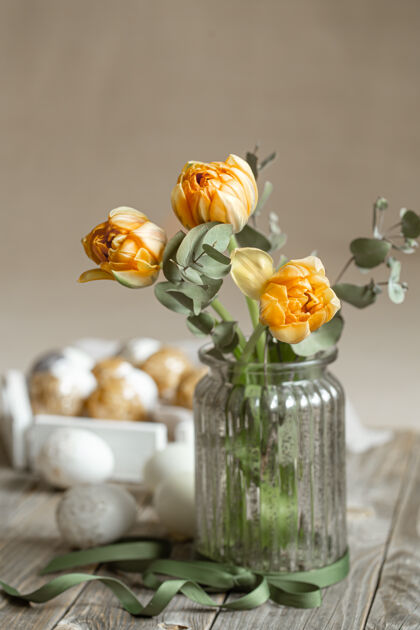 花瓶一束鲜花放在一个玻璃花瓶里 在模糊的背景上有装饰元素复活节假期的概念复活节花卉节日