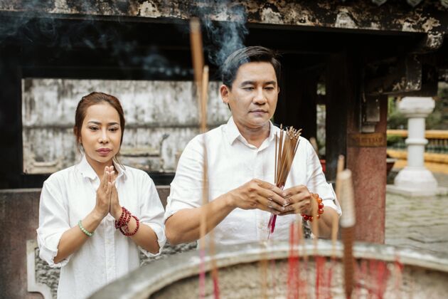 亚洲人女人和男人在寺庙里烧香祈祷的正面图有神论水平男人