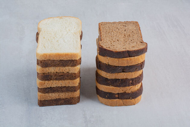 烘焙新鲜的白色和棕色面包片放在大理石背景上白色面包美味