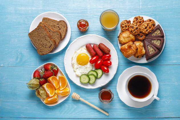 西红柿早餐盘子里有鸡尾酒香肠 煎蛋 樱桃番茄 糖果 水果和一杯桃子汁香肠蛋黄蔬菜