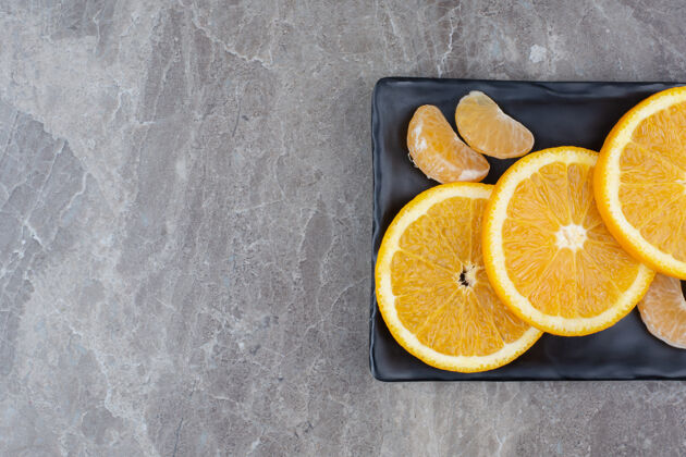 水果橘子和橘子片放在黑盘子里柑橘美味柑橘