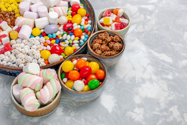 桌子正面近距离看糖果组成不同颜色的糖果和棉花糖放在白色的桌子上午餐压缩不同