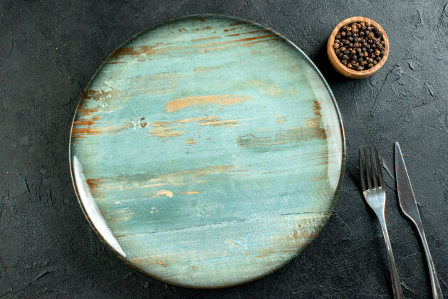 地图顶视图圆形盘子餐刀和叉子黑胡椒在碗里黑桌子上顶部全球碗