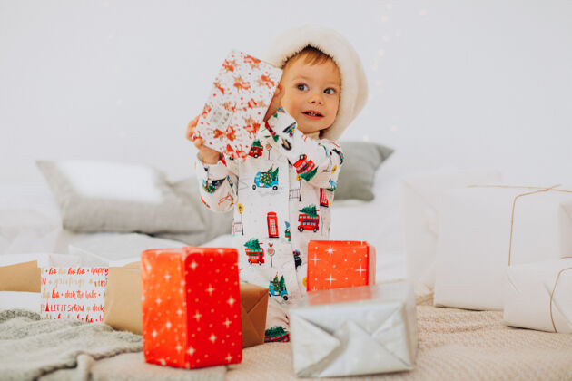 圣诞老人戴圣诞帽的可爱男孩在圣诞节打开礼物礼品盒惊喜人
